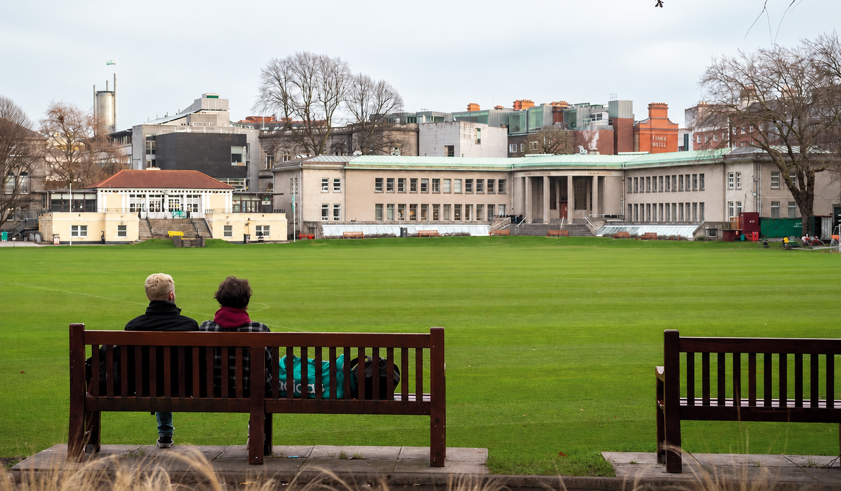 Two people sitting together on a bench overlooking the grounds at Trinity College Dublin.